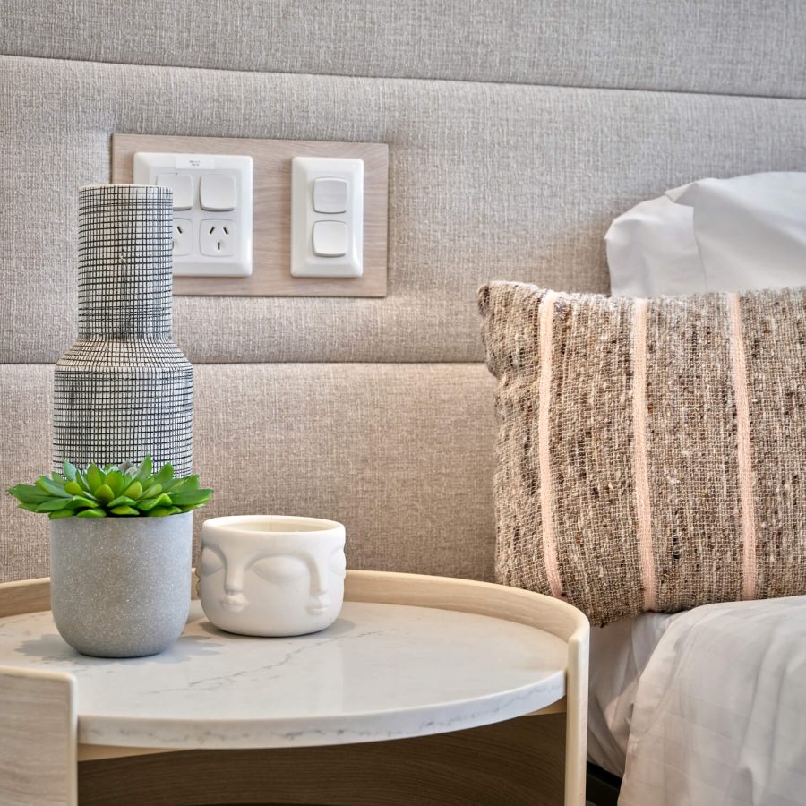 Greenwich Place Deluxe bedside table with plant, vase an large electrical buttons