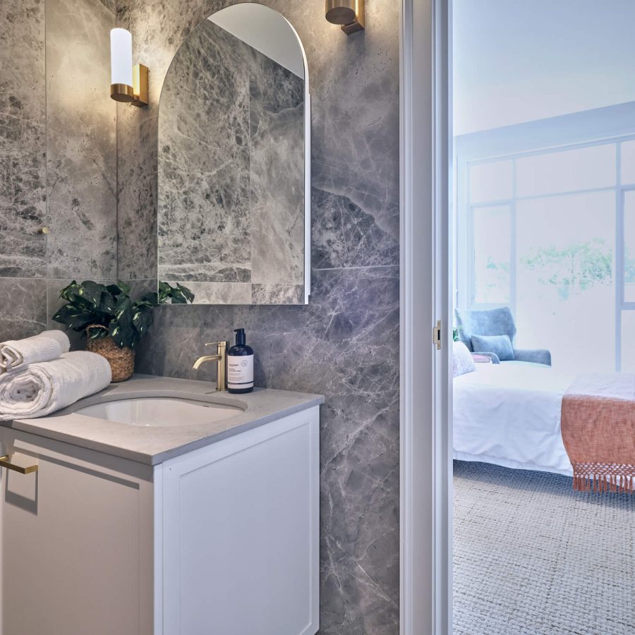 Greenwich Place Deluxe bathroom sink, mirror and towels with bed and terrace doors outside open bathroom door